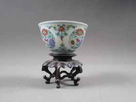 A Chinese Wucai porcelain tea bowl with six-character mark to base, 2 3/4" dia, on hardwood stand