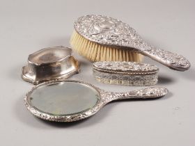 A silver backed dressing table mirror with scrolled embossed decoration, a similar brush, a silver