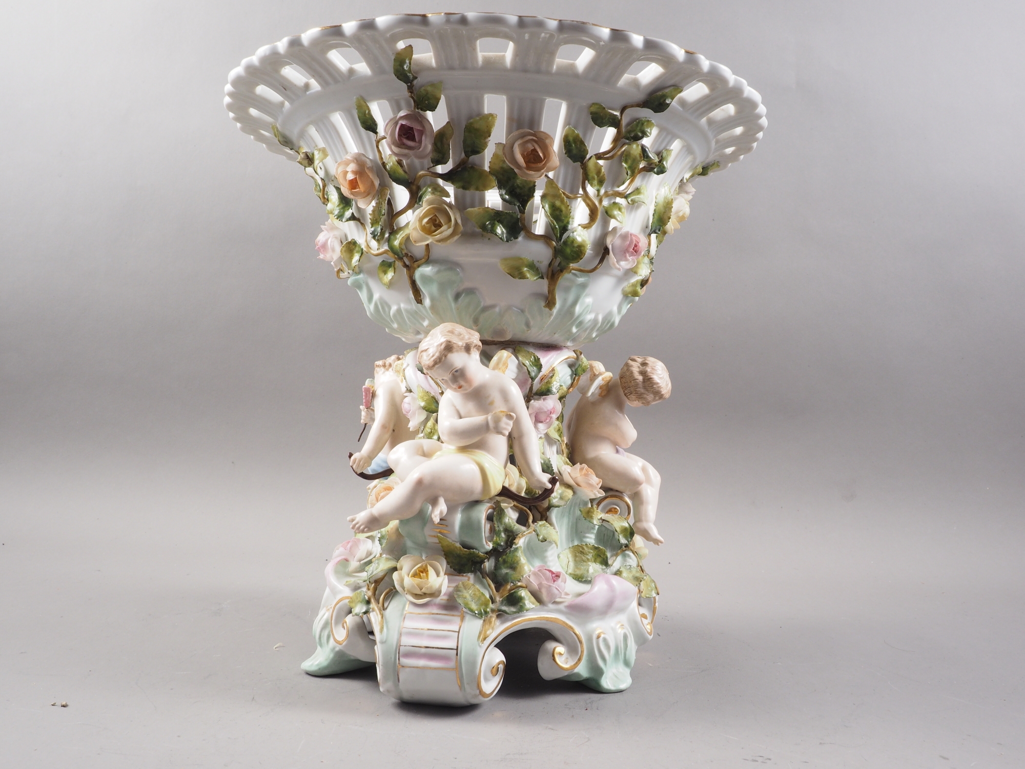 A Continental porcelain table centre with relief putti and flower decoration, on scrolled - Image 2 of 4