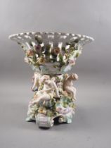 A Continental porcelain table centre with relief putti and flower decoration, on scrolled