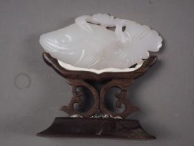 A Chinese pale celadon jade carving of a fish, 3" long, on hardwood stand