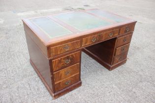 A partners figured mahogany double pedestal desk with triple panel tooled leather top over nine