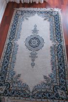 A Persian city rug with central scroll design on a cream ground and scroll borders in shades of