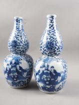 A pair of Chinese blue and white double gourd vases with panelled figure decoration on a flower