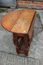 An oak drop leaf occasional table, on turned and stretchered supports, 23" wide x 25" deep x 19"