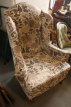 An oak wing armchair of Georgian design, fitted worn floral loose covers, on cabriole supports