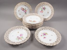 Ten KPM porcelain plates with reticulated and gilded borders and hand painted floral centres, 9" dia