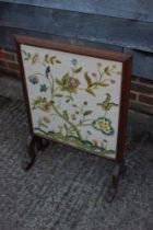 An early 20th century walnut framed firescreen with crewelwork panel end splay supports, 20" wide