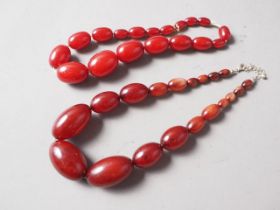 A cherry amber Bakelite bead necklace, the largest oval bead, 37mm long, 61.8g gross and another