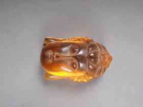 An Oriental carved amber bust of Buddha, partial signature to reverse, 1 3/4" long