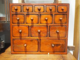 A miniature oriental hardwood chest of fourteen graduated drawers, 15" wide