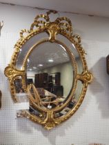 A late 19th century gilt oval framed multiple-plate wall mirror with ribbon and shell crest, 48"