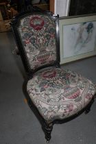 A Victorian ebonised showframe low seat chair, upholstered in a Jacquard tapestry, on turned