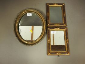 A pair of rectangular wall mirrors, in textured effect gilt frames, 6 3/4" x 4 1/4", with an oval