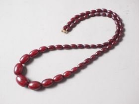 A cherry amber Bakelite bead necklace, the largest oval bead, 29mm long, 64.4g gross