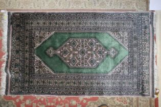 A Bokhara rug with central medallion on a green ground with multi-borders in shades of green,