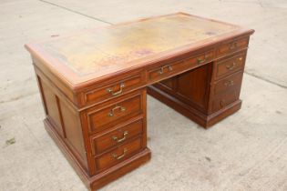 A mid 20th century walnut double pedestal desk with tooled lined top, fitted nine drawers, on