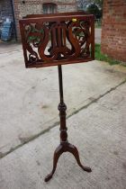 A reproduction mahogany music stand, on tripod splay support