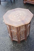 A Kashmir carved and brass inlaid hardwood octagonal occasional table, on folding support, 18" dia x