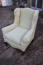 An Edwardian low seat wing back armchair, upholstered in a light green fabric