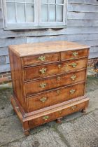 An early 18th century figured walnut and banded chest on stand, the upper section fitted two small