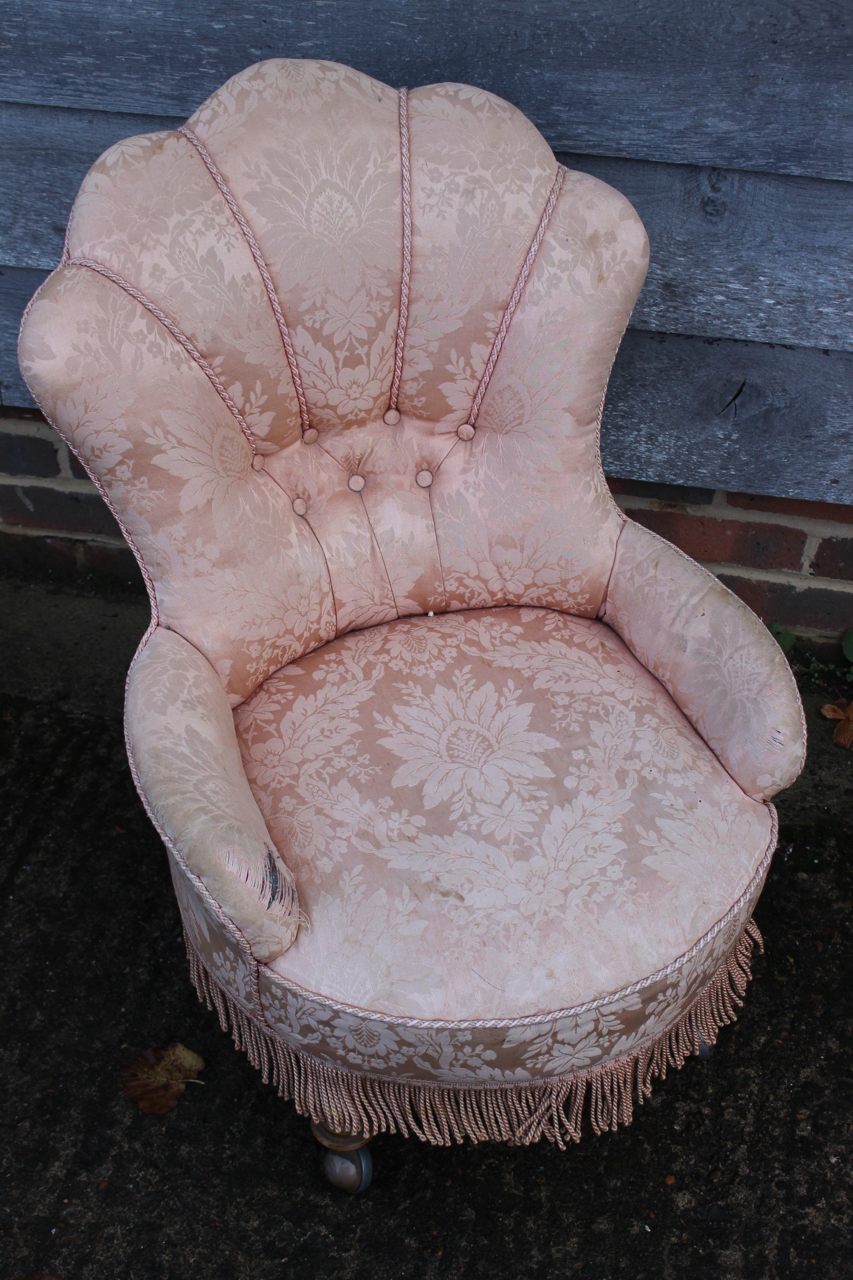 A low armchair with circular seat, button and corded shell-shaped back, upholstered in a salmon