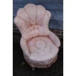 A low armchair with circular seat, button and corded shell-shaped back, upholstered in a salmon