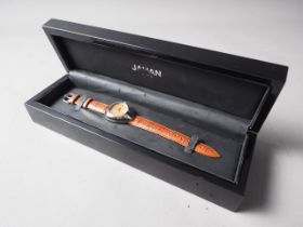 A Jahan Geneve stainless steel cased wristwatch with orange dial and baton numerals, on brown