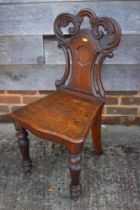 A 19th century carved oak hall chair with panel seat, on shaped supports