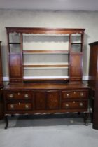 An early 19th century oak and mahogany banded dresser, the upper section fitted open shelves with