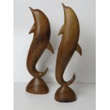 A pair of carved wooden dolphin figurines, one having repair to dorsal fin, each standing 37cm high.