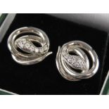 A pair of silver earrings, each in the form of a coiled snake, with white stone heads,