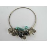 A white metal bangle having turquoise and quartz beads upon.