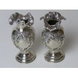 A pair of Chester hallmarked silver short bud vases having repoussé floral decoration and standing