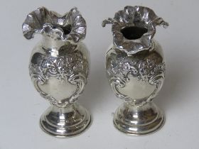 A pair of Chester hallmarked silver short bud vases having repoussé floral decoration and standing