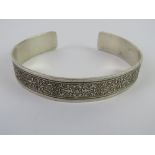 A HM silver bangle having carved foliate pattern upon,