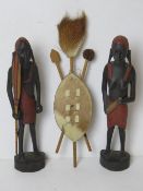 A pair of African carved figures together with an animal hide shield.