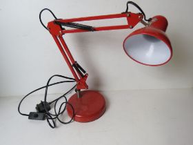 A red metal angle poise style table lamp.