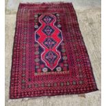 A 100% woollen rug in red ground having geometric pattern and measuring approx. 220 x 136cm.