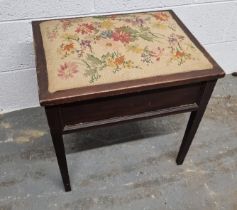 A piano stool having floral embroidered seat pad opening to reveal compartment within, 51cm wide.