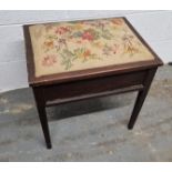 A piano stool having floral embroidered seat pad opening to reveal compartment within, 51cm wide.