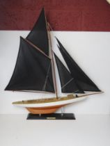 A model pond yatch 'Columbia' having black sails, approx 82cm in length.