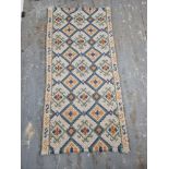 A hand woven rug in yellows, blues and greens measuring approx. 142 x 70cm.