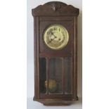 An oak cased hanging wall clock having brass dial and black Arabic numerals, pendulum within,