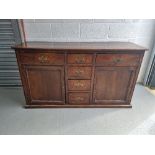 An oak dresser base having four central drawers with drawer and door flanking,