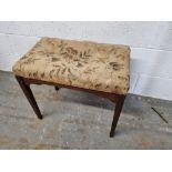 A piano stool with floral fabric seat.
