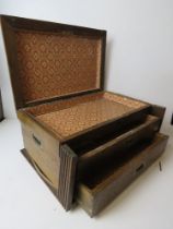 A tabletop campaign box, lid lifting to reveal lined interior with two drawers below,