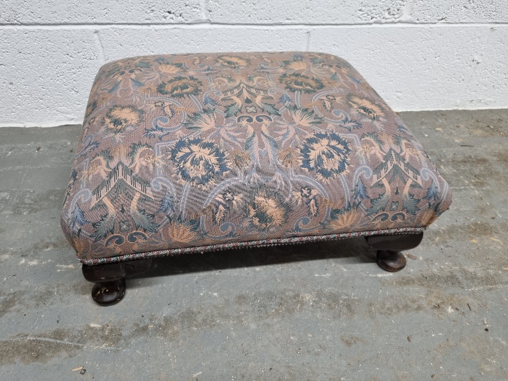 A low footstool upholstered in blue and purple fabric in the Liberty style.