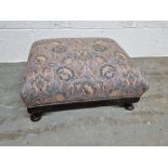 A low footstool upholstered in blue and purple fabric in the Liberty style.