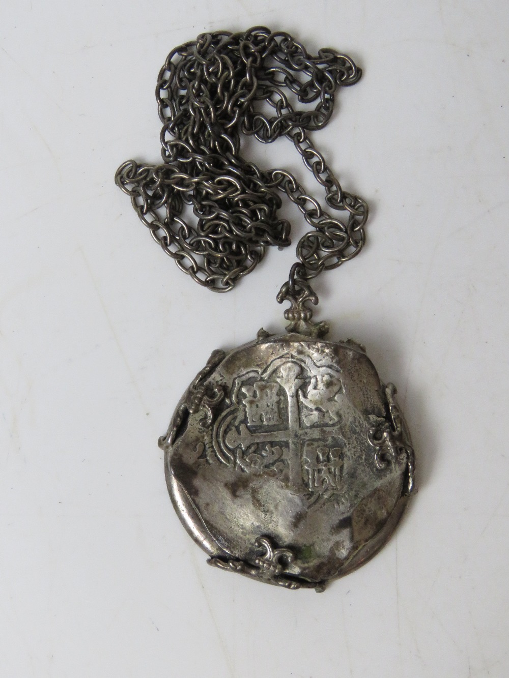 An antique coin in a/f condition, mounted in hallmarked silver frame on unmarked white metal chain,